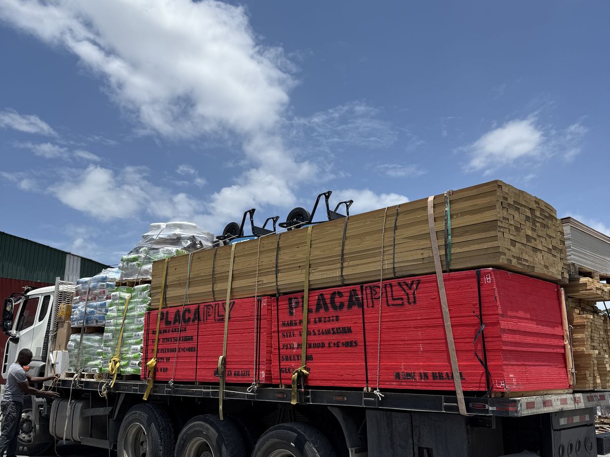 A loaded flatbed of plywood, lumber and cement leaving the yard